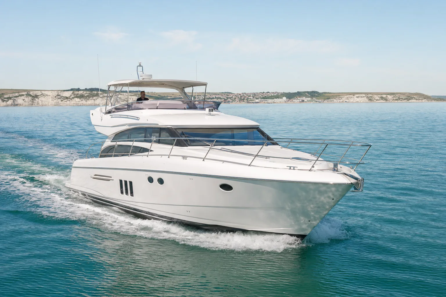 A white motor yacht cruising on calm water off the English south coast